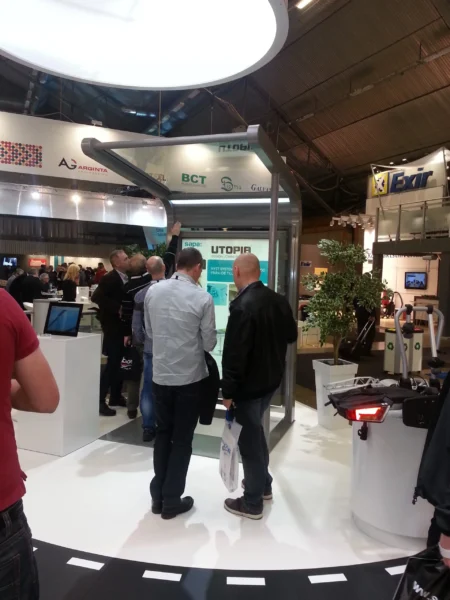 Die Wartehalle UTOPIA, ausgestellt auf einer Messe, umgeben von interessierten Besuchern.