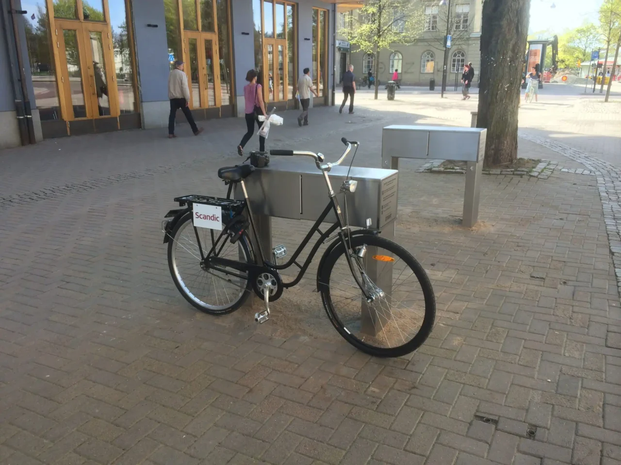 Fahrradständer aus Metall mit Ablagefach und angeschlossenem Fahrrad in der Stadt.