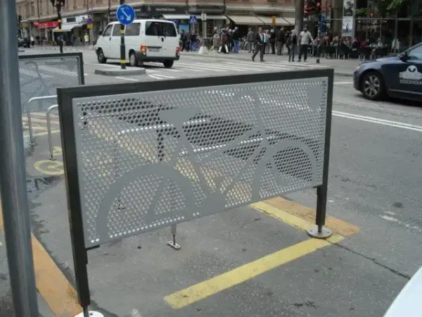 Mehrere Fahrradständer neben einer Hauptstraße in Stockholm, im Hintergrund Autos und Menschen.